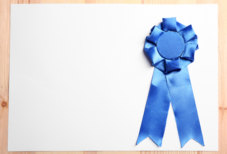 Award ribbon on white paper sheet, on wooden backgroundの写真素材