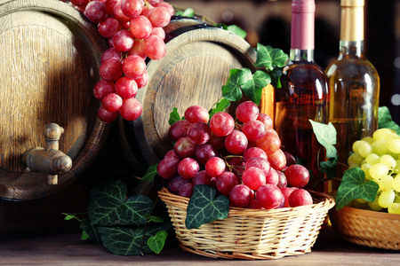 Grapes in bowls and barrel on wooden table
