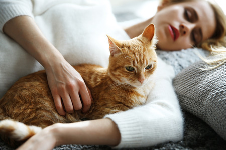 Attractive woman laying with red catの写真素材
