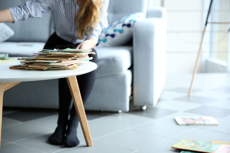 Pile of old books on white table. Woman throws books from table.