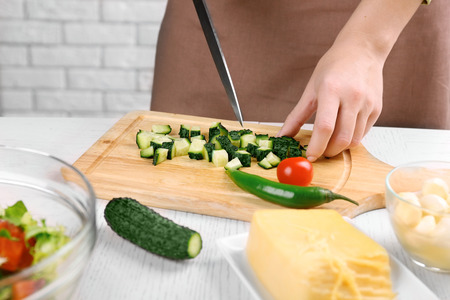 Female hands cutting vegetables for salad, at kitchenの写真素材