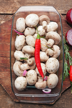Marinating mushrooms with spices on wooden tableの写真素材