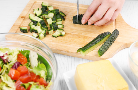 Female hands cutting vegetables for salad, at kitchenの写真素材