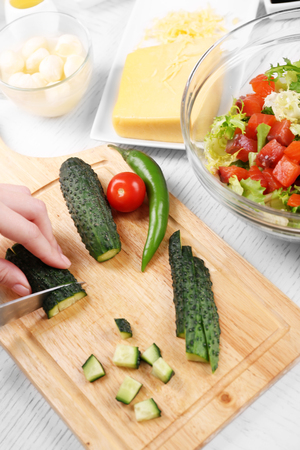 Female hands cutting vegetables for salad, at kitchenの写真素材