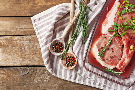 Marinating meat with spices on wooden tableの写真素材