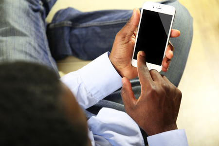 Afro american man with a smartphone indoorの写真素材