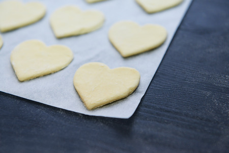 Uncooked heart shaped biscuits on a baking paperの写真素材