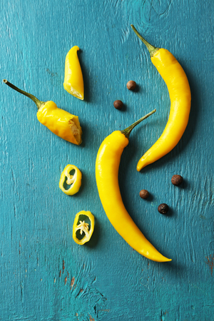 Yellow chili peppers on color wooden backgroundの写真素材