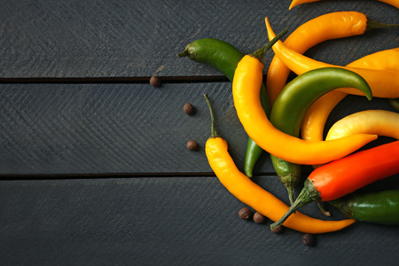 Yellow chili peppers on wooden background