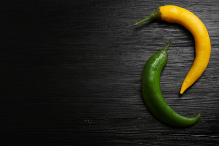 Yellow and green chili peppers on dark wooden backgroundの写真素材