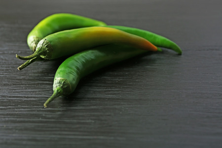 Green chili peppers on dark wooden backgroundの写真素材