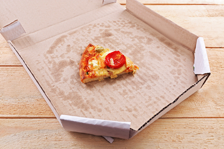 Slice of delicious pizza in cardboard on tableの写真素材