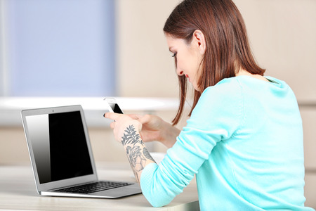 Woman sitting at the table and working with laptopの写真素材