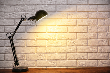 Modern lamp on table on brick wall backgroundの写真素材