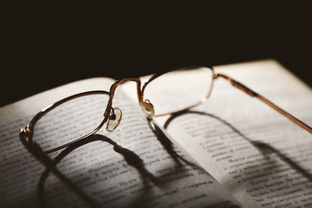Opened book and eyeglasses on it, close up