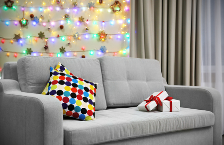 Grey couch with pillow and gifts on Christmas lights backgroundの写真素材