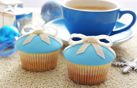 Tasty cupcakes with bow, coffee cup and Christmas toys on color wooden backgroundの写真素材
