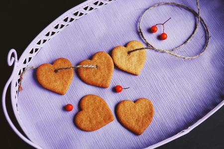 Heart shaped biscuits with ash berries on a lilac tray, top viewの写真素材