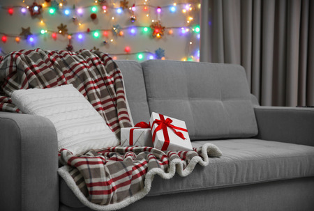 Grey couch with pillow and gifts on Christmas lights backgroundの写真素材