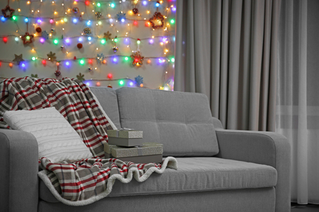 Grey couch with pillow and gifts on Christmas lights backgroundの写真素材