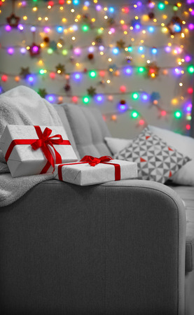 Grey couch with gifts on Christmas lights backgroundの写真素材