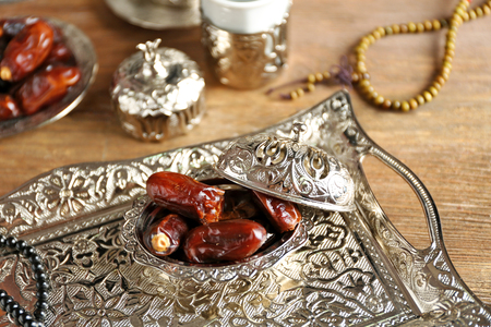 Composition of dried dates in holiday dish and rosary on wooden background closeupの写真素材
