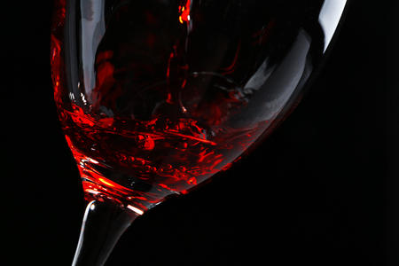 Pouring red wine on dark backgroundの写真素材