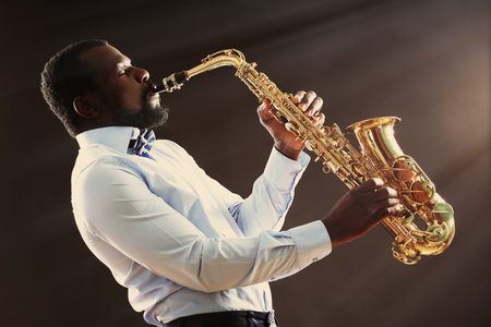 African American jazz musician playing the saxophone on grey backgroundの写真素材