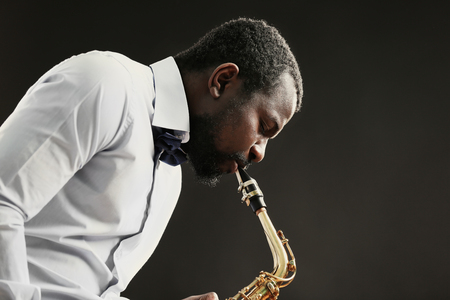 African American jazz musician playing the saxophone on grey backgroundの写真素材