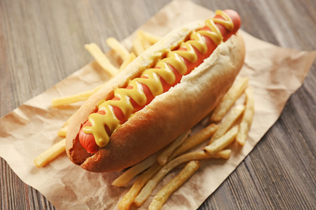 Hot dog with fried potatoes on craft paperの写真素材