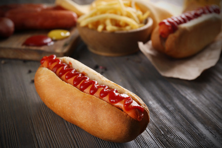 Hot dog with fried potatoes and fresh sausages on wooden backgroundの写真素材