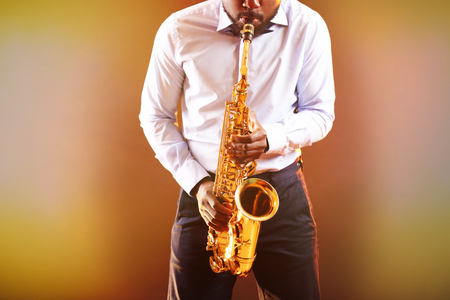 African American jazz musician playing the saxophone on ginger backgroundの写真素材
