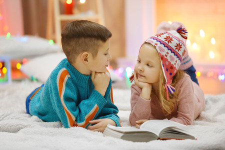 Cute children read book on the floor in the decorated Christmas roomの写真素材