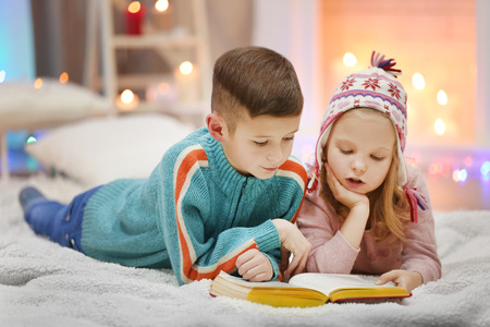 Cute children read book on the floor in the decorated Christmas roomの写真素材