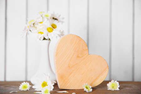 Wooden heart with flowers on a white wall backgroundの写真素材