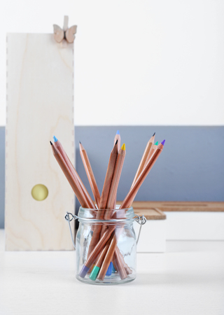 Set of coloured pencils in a glass pot on a tableの写真素材