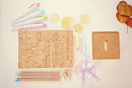 Set of coloured pens, pencils, stickers with notebook on white tableの写真素材