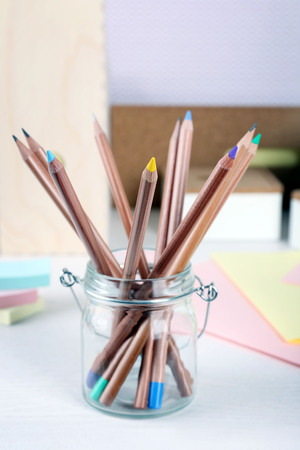 Set of coloured pencils in a glass pot on a tableの写真素材