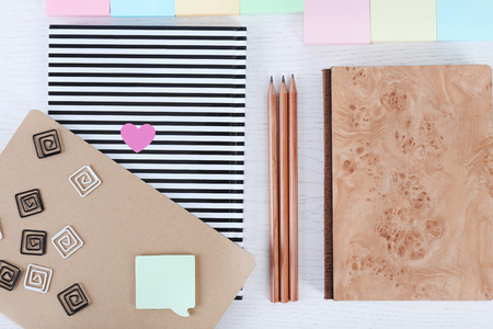 Notebooks with clips, stickers and pencils on a white tableの写真素材