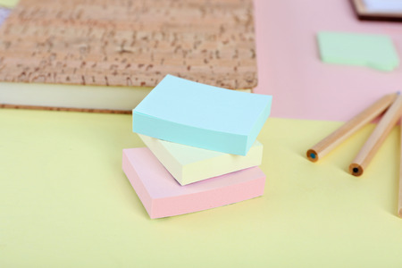 Pencils, stickers and notebook on coloured paper