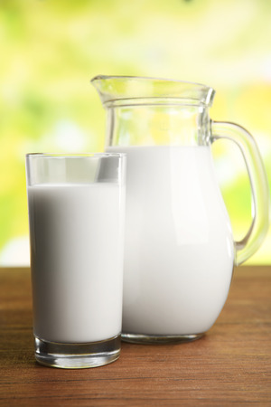 Milk in jar and in glass on table on blurred natural backgroundの写真素材