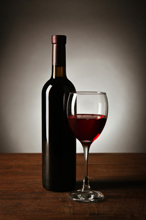Wine in glass and in bottle on table on dark backgroundの写真素材