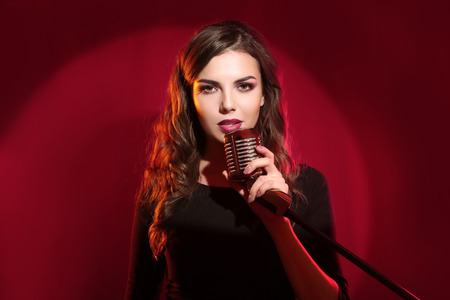 Attractive female singer on red background, close upの写真素材
