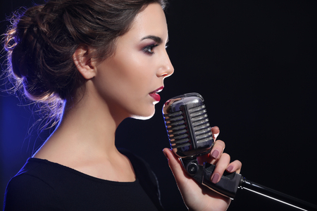 Portrait of beautiful singing woman on dark backgroundの写真素材