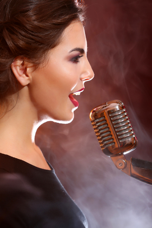 Elegant woman singing in colourful smoke, close upの写真素材
