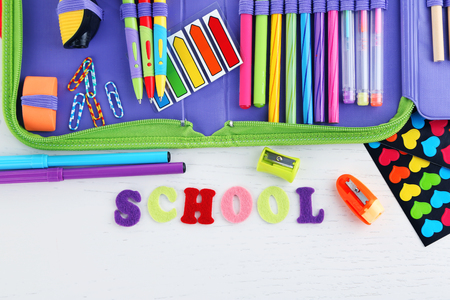Pencil case with various stationery on wooden table