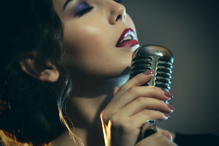 Beautiful brunette woman singing on grey backgroundの写真素材