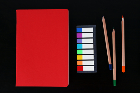 Notebook with coloured pencils and ruler on black tableの写真素材