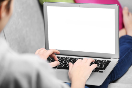 Woman sitting on sofa with a laptop in a roomの写真素材