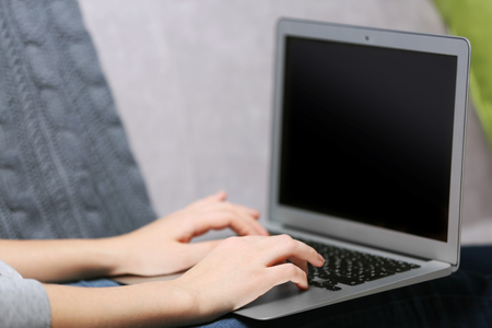 Woman sitting on sofa with a laptop in a roomの写真素材